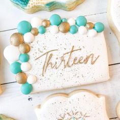 decorated cookies with the word thirteen displayed in gold, white and blue frosted icing