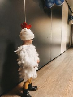 a little boy dressed up as a chicken wearing a white hat and feathery coat