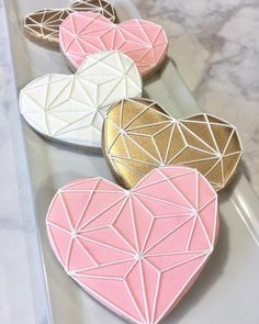 three heart shaped cookies sitting on top of a white plate with pink and gold decorations