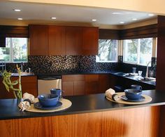 a kitchen with wooden cabinets and black counter tops, along with blue dishes on plates