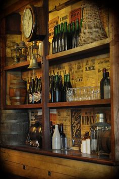 the shelves are full of bottles and other items in front of a wall with an old clock on it