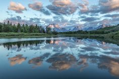 the mountains are reflected in the still water of this lake as the sun goes down