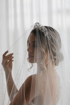 a woman wearing a wedding veil and holding her hand up to her face