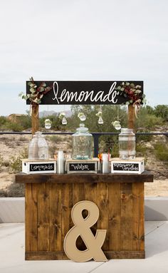 an outdoor dessert bar with jars and candles on it, decorated with flowers and greenery