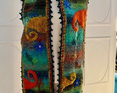 a multicolored knitted scarf hanging on a hook in front of a door