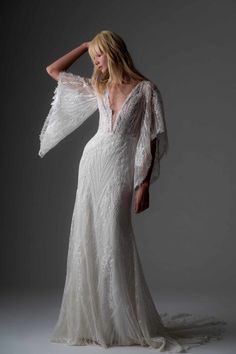 a woman in a white wedding dress posing for the camera with her arms behind her head