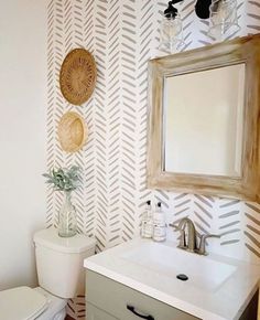 a white toilet sitting under a bathroom mirror next to a wooden sink faucet