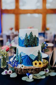 a three tiered cake with trees and mountains on it sitting on top of a table