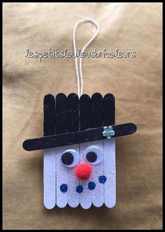 an ornament made out of pops sticks with a snowman face