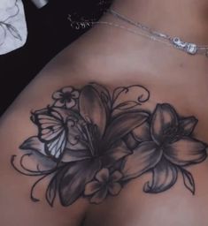 a woman's back with flowers and butterflies tattoo on her left side ribcage