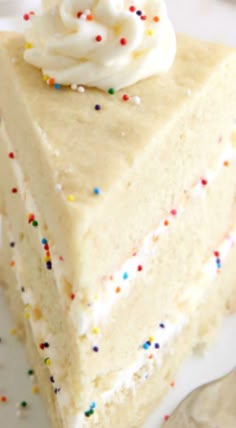 a slice of cake with white frosting and sprinkles