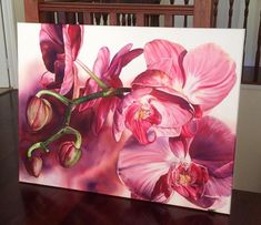 a painting of pink orchids on a white canvas with wood flooring in the background