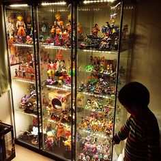 a boy standing in front of a display case filled with toys