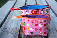 two hello kitty bags sitting on top of a wooden table