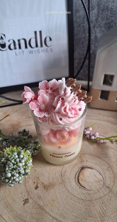 a jar filled with pink flowers sitting on top of a wooden table next to a plant