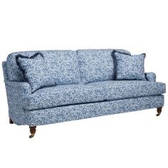 a blue and white floral couch with pillows on it's back end, sitting in front of a white background