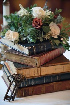 a stack of books sitting on top of each other with flowers and greenery in them