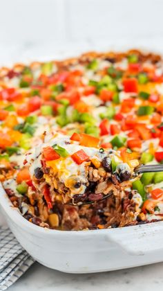 a casserole dish filled with meat, vegetables and cheese on a white surface