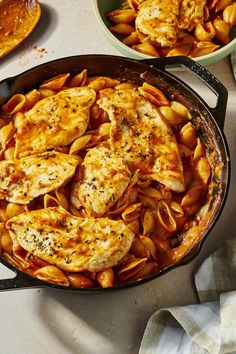 a skillet filled with pasta and chicken on top of a white counter next to other dishes