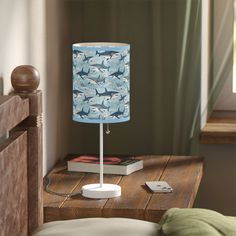 a blue lamp sitting on top of a wooden table next to a bed in a bedroom