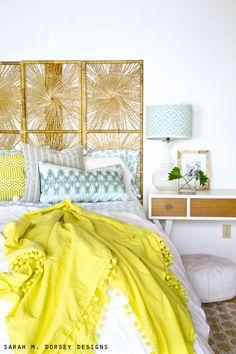 a bed with yellow and blue pillows on it's headboard in a bedroom