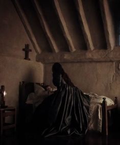 a woman sitting on top of a bed in a room with exposed ceiling and walls