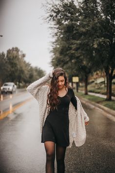 a woman walking down the street in the rain with an open jacket over her shoulders