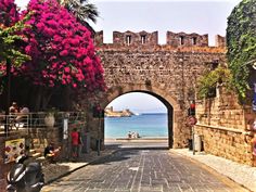 an archway leading to the ocean with people sitting on scooters in front of it