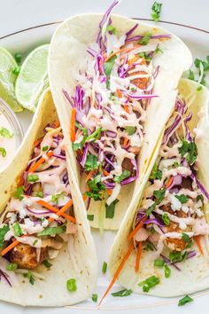 three fish tacos with cole slaw, carrots and cilantro sauce