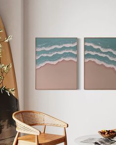 two paintings hang on the wall above a table