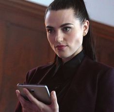 a woman is looking at her phone while wearing a black shirt and purple blazer