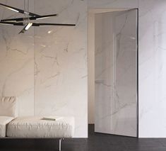 a white couch sitting in front of a wall mounted ceiling fan next to a mirror