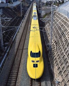 a yellow train traveling down tracks next to an industrial area