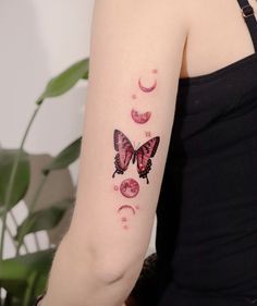 a woman's arm with a butterfly and crescent moon tattoos on the left side of her arm