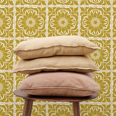 three pillows stacked on top of each other in front of a wallpapered background