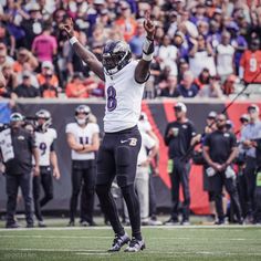 a football player holding his hands up in the air with one hand and two fingers raised