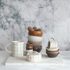 several bowls and cups stacked on top of each other in front of a marble background