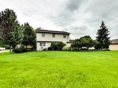 a large grassy yard with two houses in the background