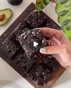 a person holding a piece of chocolate cake in front of an avocado plant