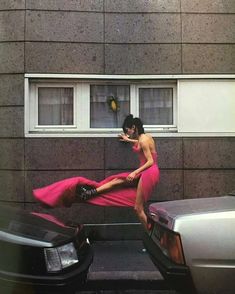 a woman in a pink dress sitting on the back of a car