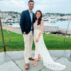 a man and woman standing next to each other in front of a marina with boats