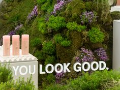 there is a sign that says you look good on the side of a wall with flowers