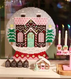 a christmas ornament is displayed on a mantle with candles and gingerbread houses