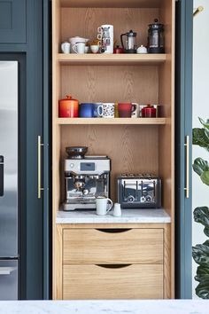 the coffee maker is sitting on top of the counter in front of the open cupboard