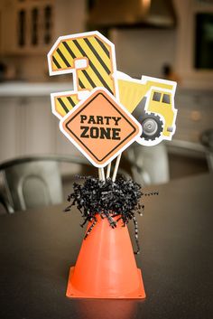 there is a party zone sign on top of an orange cone in the middle of a table