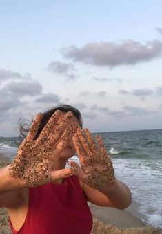 a woman covering her eyes with sand on the beach