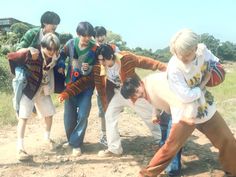 a group of young men standing next to each other on a dirt road