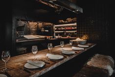 a table with plates, wine glasses and utensils on it in a kitchen