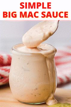 a jar filled with white sauce sitting on top of a wooden table next to a spoon