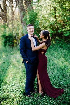 a young man and woman in formal wear standing next to each other on the grass